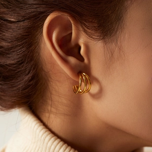 Close-up of gold three-layered C-shaped earrings on model for a minimalist jewelry style