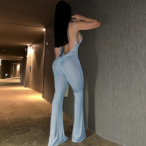 Rear view of light blue backless jumpsuit with ruched details and flared legs in a corridor