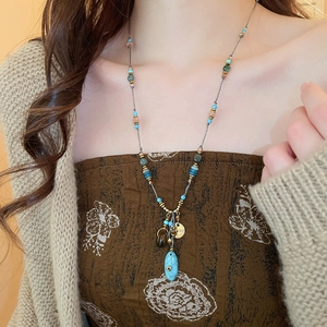 Dettaglio della collana di perle boho con ciondolo a forma di occhio turchese su modella