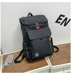 Detail of black tactical backpack featuring orange zipper pulls and Spunk woven label