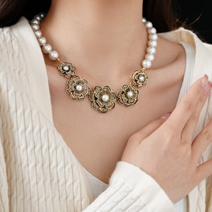 Detailed view of vintage flower necklace with artificial pearls worn by model
