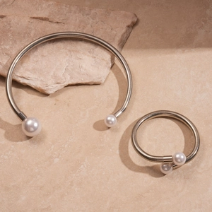 Metallic geometric choker and bracelet set with faux pearls on stone background