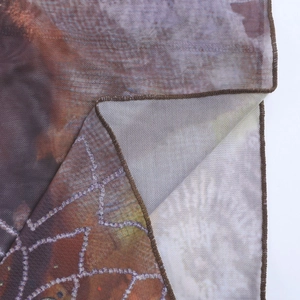 Gros plan détaillé sur un tissu en maille respirant avec imprimé vintage et ourlet brun