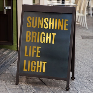 Detail of a black folding A-frame sign with premium gold foil lettering for outdoor display