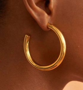 Close-up of chunky gold C-shaped hoop earrings with a polished minimalist finish