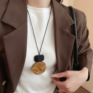 Detail of a geometric resin pendant necklace with marble texture on a long black leather cord