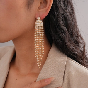 Close-up of long gold fringe earrings with sparkling zircons worn by a female model