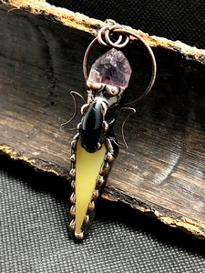 Detail of vintage bronze wire-wrapped pendant with amethyst and black agate on bark