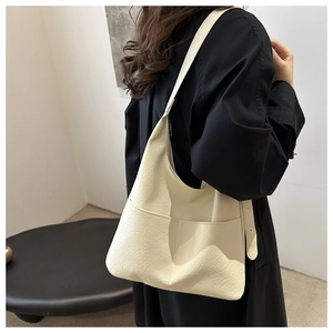 Detailed view of cream white tote bag with fine leather texture worn by a model