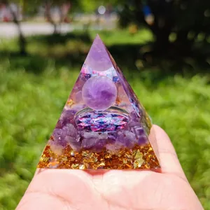 Macro shot of an Orgone energy pyramid with amethyst ball and gold foil held in hand