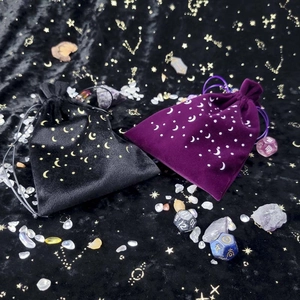 Close-up of black and purple velvet tarot bags with gold star and moon patterns