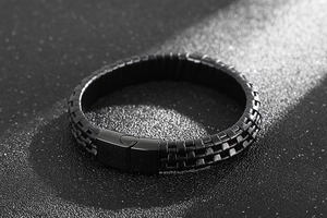 Macro detail of men's braided leather bracelet with engraved G magnetic steel clasp