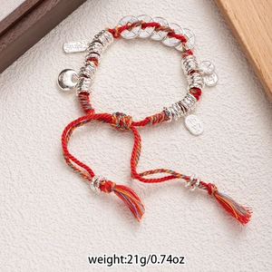 Macro detail of red woven bracelet with silver coins and auspicious charms, 21g weight