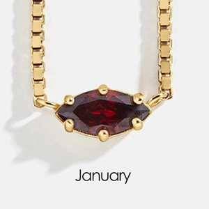 Macro shot of an 18K gold plated box chain necklace with a January red garnet pendant