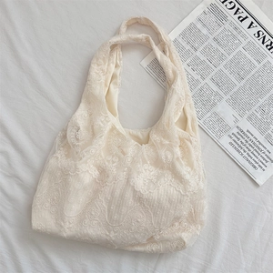 Detail of delicate off-white lace floral embroidery on a soft hobo style tote bag