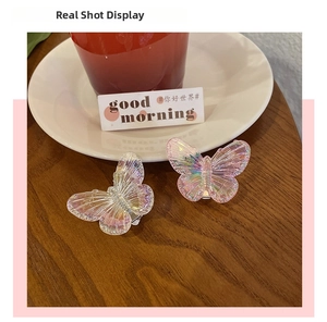 Close-up of two iridescent butterfly hair clips with a vibrant holographic finish