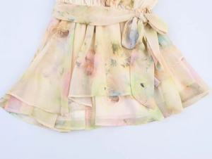 Dettaglio di abito in chiffon floreale con fiocco in vita e gonna a balze a strati