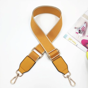 Detail of yellow woven bag strap with PU leather ends and adjustable gold hardware