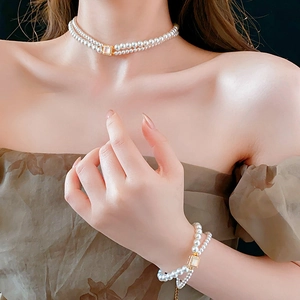 Detail showing double-layered pearl necklace and bracelet set with gold plating