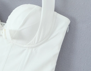 Detailansicht eines weißen Neckholder-Kleides mit seitlichem Reißverschluss und Struktur
