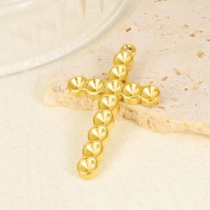 Detailed macro shot of a gold-plated stainless steel cross pendant with dotted texture