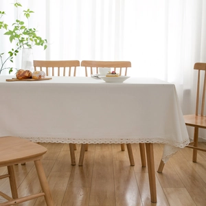 Natural off-white cotton linen tablecloth with delicate lace trim on a rustic wooden table