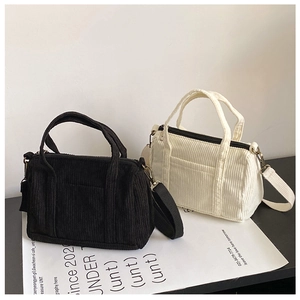 Close-up of black and cream corduroy Boston bags with soft texture and top handles