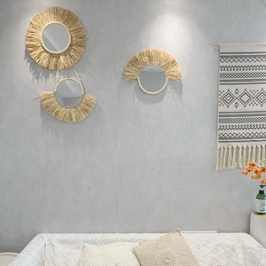 Dettaglio di specchi da parete in rafia con frange in paglia naturale e perline decorative
