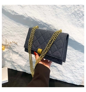 Detailed view of blue denim quilted shoulder bag with gold hardware and chain strap