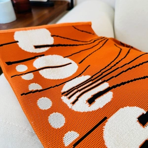 Close-up of orange knitted fabric showing white dotted texture and black line details