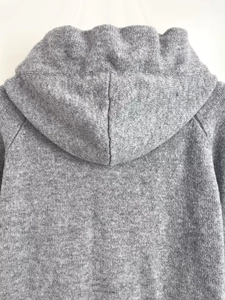 Detail shot of grey knitted hoodie showing fabric texture and hood seam on back
