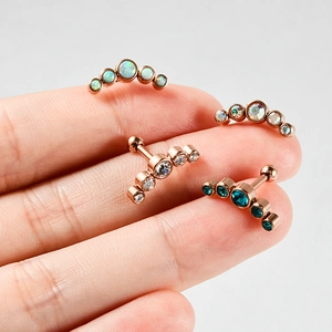Macro view of curved five-stone stud earrings in rose gold finish with opal and crystals
