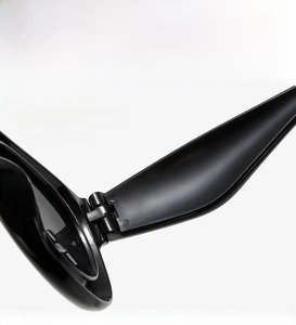 Detailed close-up of sturdy metal hinge on glossy black round sunglasses frame