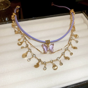 Close-up of triple-layered butterfly and seashell necklace with purple cord and zircons