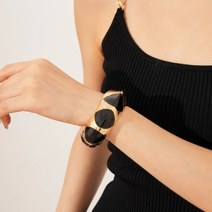 Detail of vintage oval gold-toned bangle with black enamel inlays on model wrist