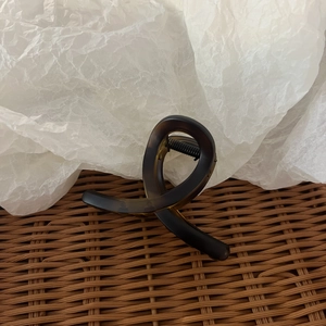 Macro view of a dark amber tortoise shell hair claw clip with a twisted figure-8 design