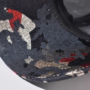Macro detail of camouflage baseball cap brim with metallic glitter and precise stitching