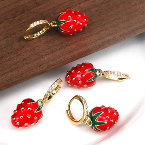 Detail of red strawberry earrings with green leaves, gold metal and sparkling crystals