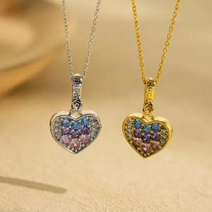 Elegant gold and silver heart necklaces with colorful cubic zirconia on wooden background
