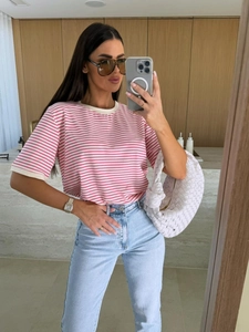 Détail d'un t-shirt à manches courtes rayé rose et blanc avec un jean bleu denim