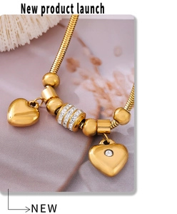 Makroaufnahme des goldenen Schlangenkettenarmbands mit Herzanhängern und weißen Kristallen