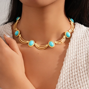Gros plan d'un collier doré vintage avec des pierres ovales bleues porté par un mannequin