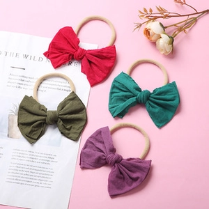 Set of four soft nylon baby headbands with large fabric bows in vibrant assorted colors