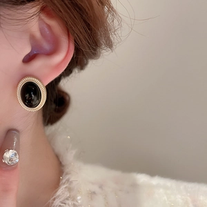 Macro view of vintage oval gold-tone earring with black onyx stone on a model ear