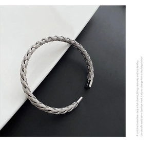 Detail of silver woven stainless steel cuff bracelet with textured metallic braided pattern