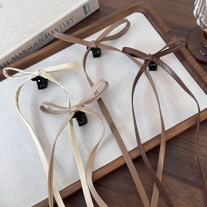 Detail of faux leather bow hair claws with long ribbons in assorted neutral tones
