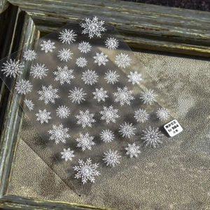 Detail showing 5D embossed white snowflake nail art stickers with a textured finish
