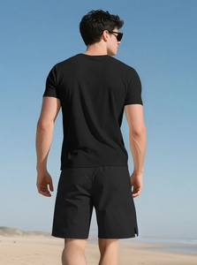 Outdoor shot of men's black Henley t-shirt and matching sports shorts on a sunny beach