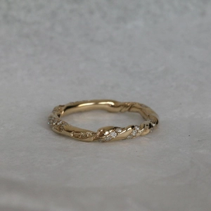 Detail of twisted gold ring band featuring clear zircon stones in a retro luxury style