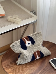 Gros plan sur la toison d'agneau bouclée et le motif de chien d'un sac bandoulière